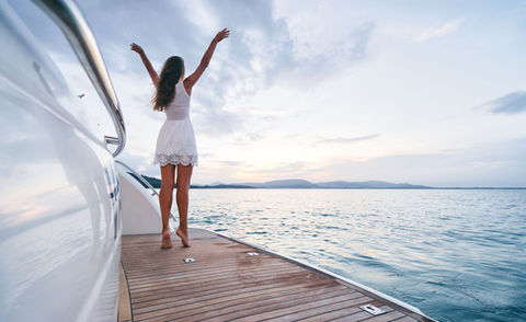 happy woman on a yacht has high arms and enjoys the sky