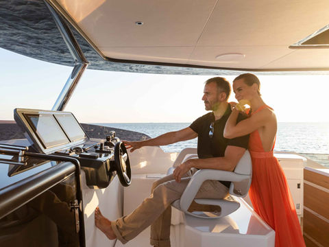 Couple on a luxury Sirena yacht with e-Motion Hybrid System; man at the helm.